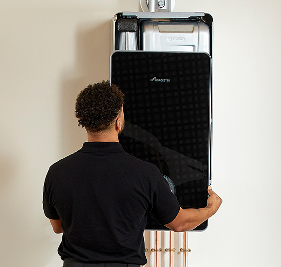 Engineer Fitting Black Worcester Boiler On Wall